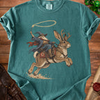 Wizard riding a jackalope with antlers, lasso in hand, on teal t-shirt.