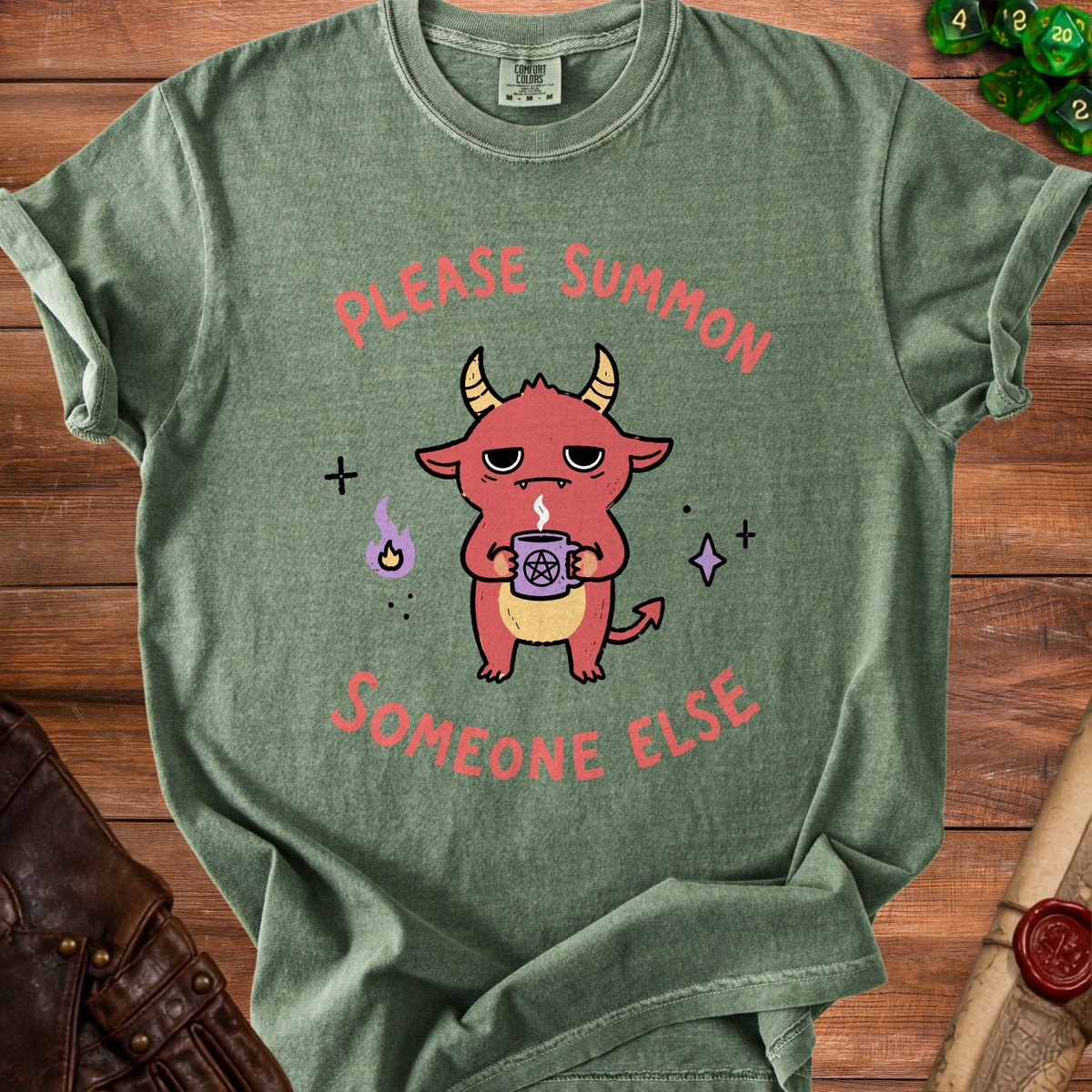 Green t-shirt with a cartoon demon holding a pentagram mug, saying "Please Summon Someone Else".
