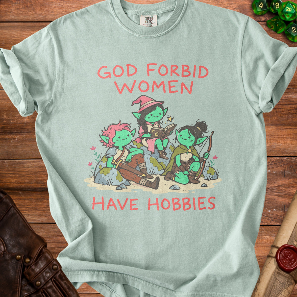 Light mint t-shirt with red text "GOD FORBID WOMEN HAVE HOBBIES" and cartoon goblins.