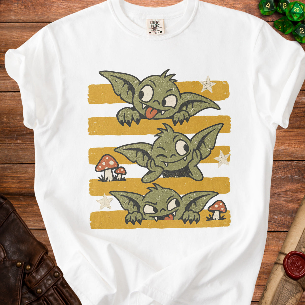 White t-shirt with three mischievous green goblins peeking over yellow stripes.