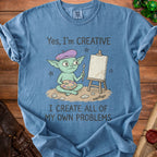 Blue t-shirt with a cartoon goblin artist and the text "Yes, I'm CREATIVE I CREATE ALL OF MY OWN PROBLEMS."