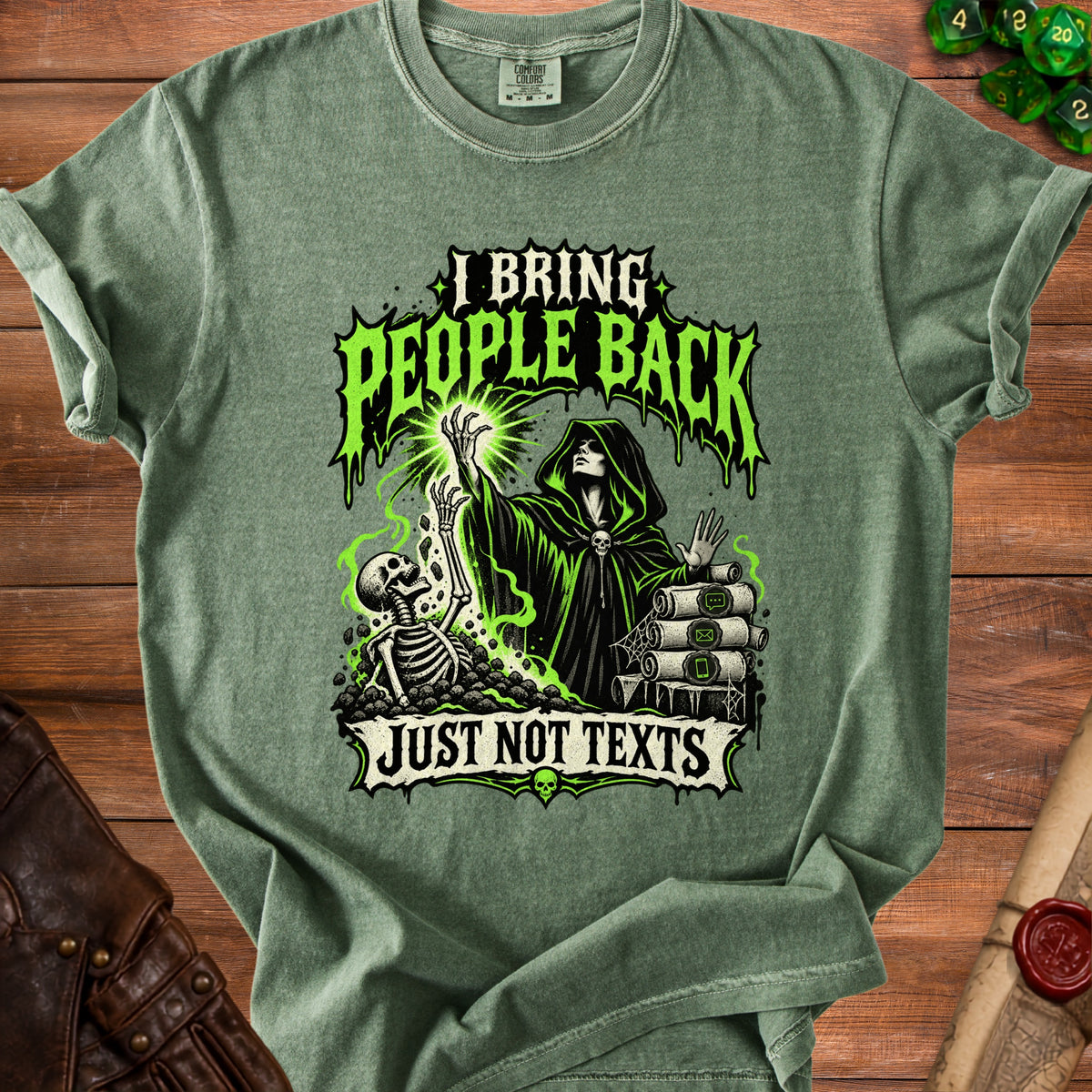 A green t-shirt with a hooded necromancer graphic, a skeleton, scrolls, and text saying I BRING PEOPLE BACK JUST NOT TEXTS.