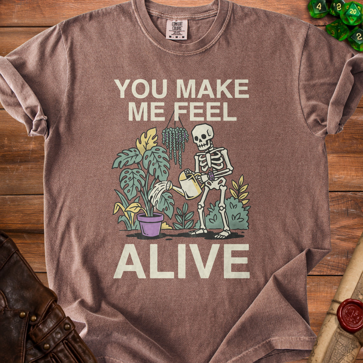 Skeleton watering plants with text "YOU MAKE ME FEEL ALIVE".