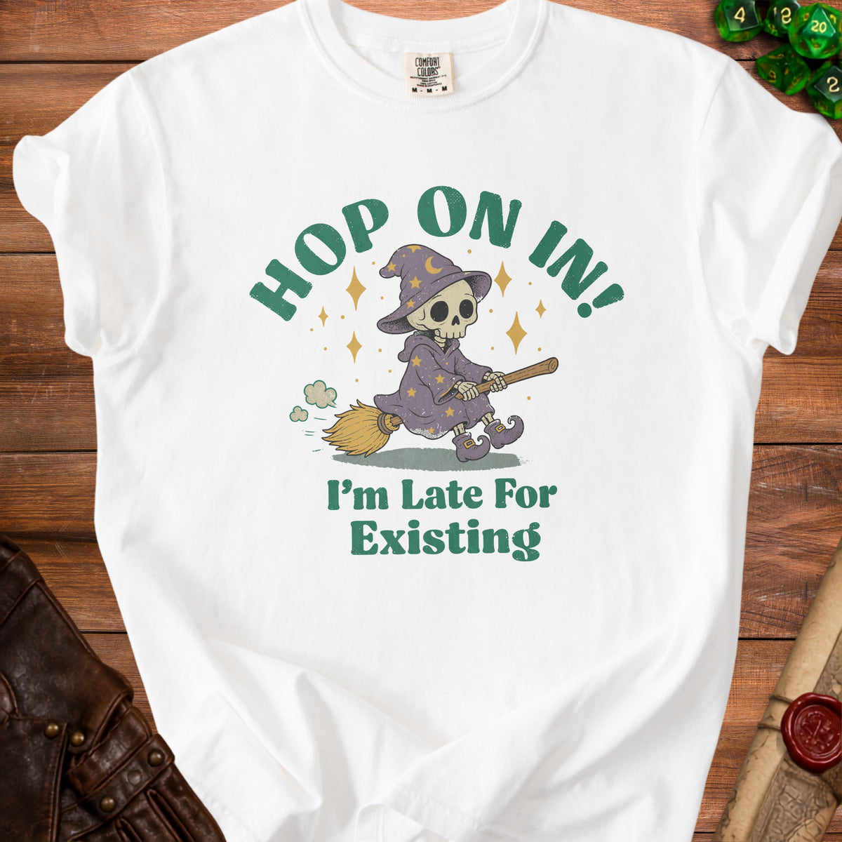 White t-shirt with graphic of skeleton wizard flying on broom, saying "Hop On In! I'm Late For Existing."