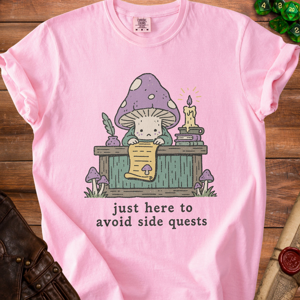 Pink t-shirt with a cartoon mushroom reading a scroll, text says "just here to avoid side quests".