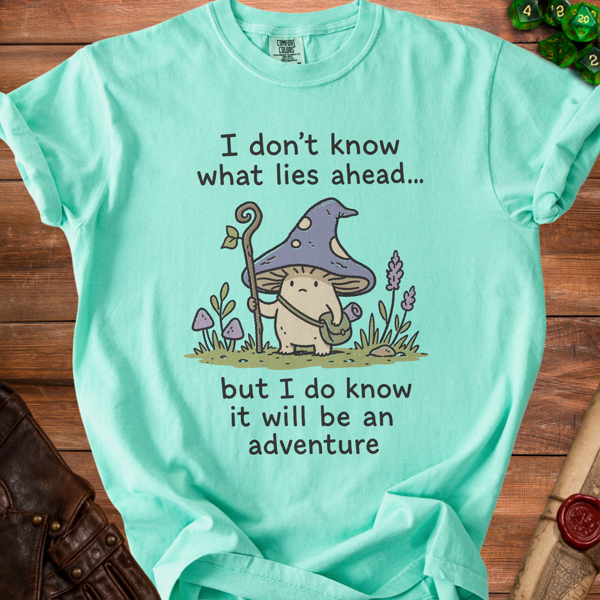 Teal t-shirt with mushroom character text "I don't know what lies ahead... but I do know it will be an adventure."