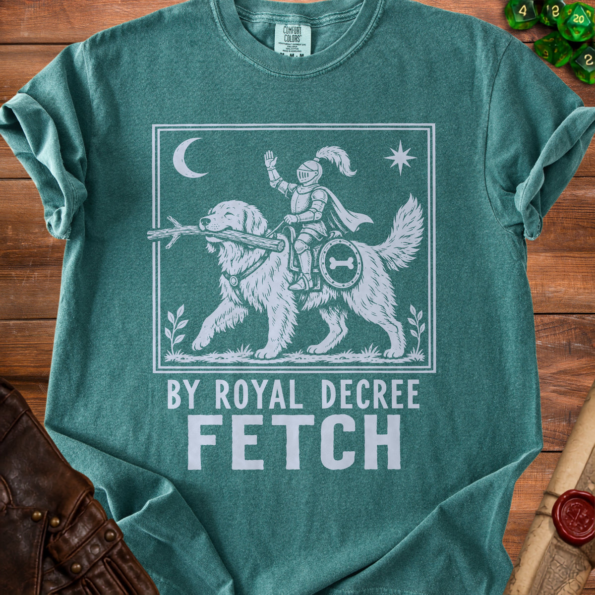 Green t-shirt with white graphic of dog carrying stick, knight on dog's back, "BY ROYAL DECREE FETCH".