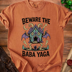 Orange t-shirt with "Beware the Baba Yaga" text and a creepy, bat-winged house.