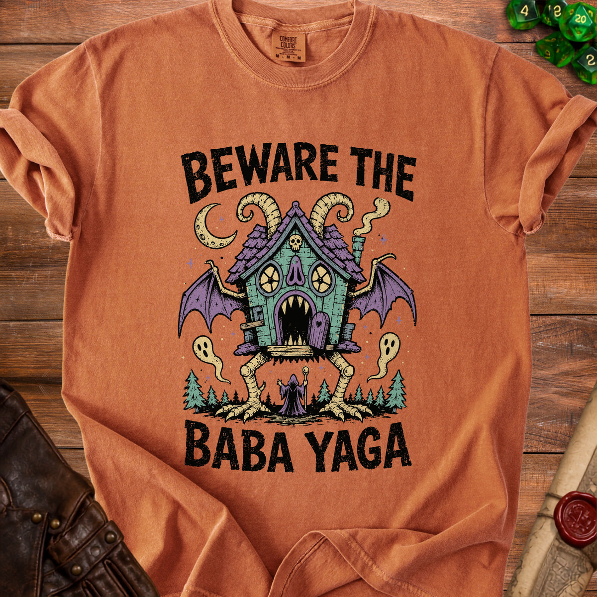 Orange t-shirt with "Beware the Baba Yaga" text and a creepy, bat-winged house.