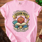 Pink t-shirt with a graphic of a D20 dice, books, and dice, reading "Session Prep Mostly Vibes".