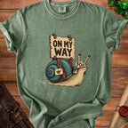 T-shirt with graphic of a snail wearing armor, carrying a satchel and a sign reading "ON MY WAY".