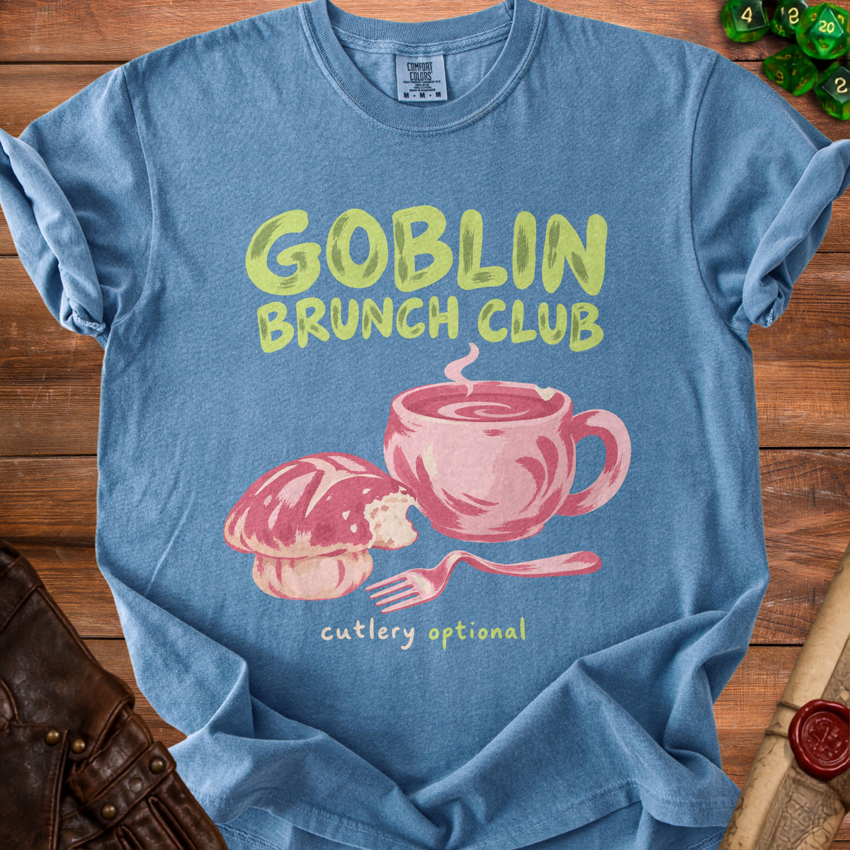 Blue t-shirt with "Goblin Brunch Club" text and a pink mug and bread illustration.