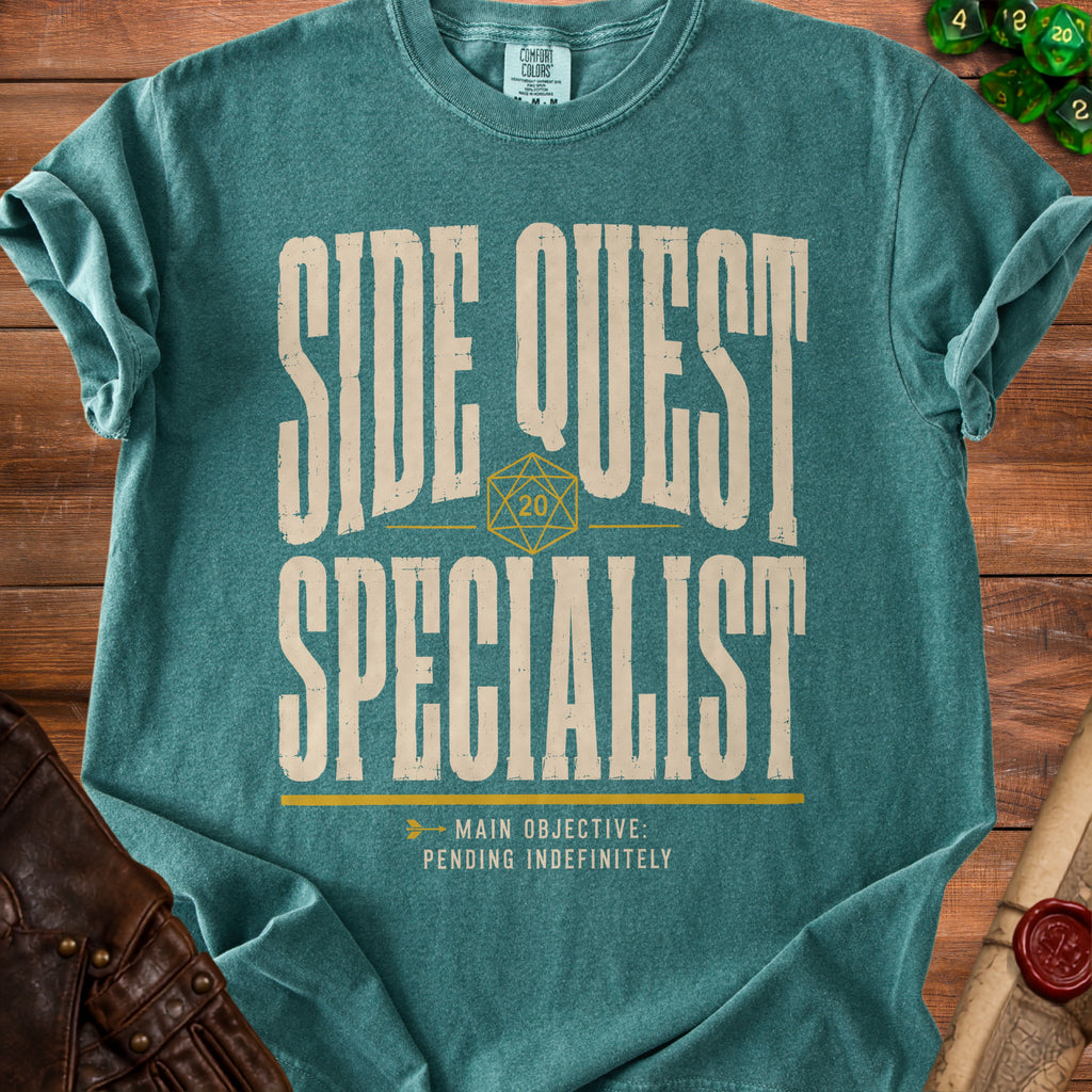 Teal t-shirt with "SIDE QUEST SPECIALIST" and "MAIN OBJECTIVE: PENDING INDEFINITELY" text.