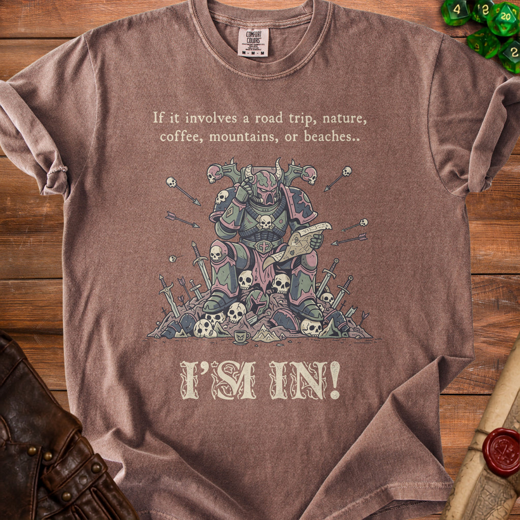 T-shirt with illustration of armored figure surrounded by skulls, text reads "If it involves a road trip, nature, coffee, mountains, or beaches.. I'M IN!".