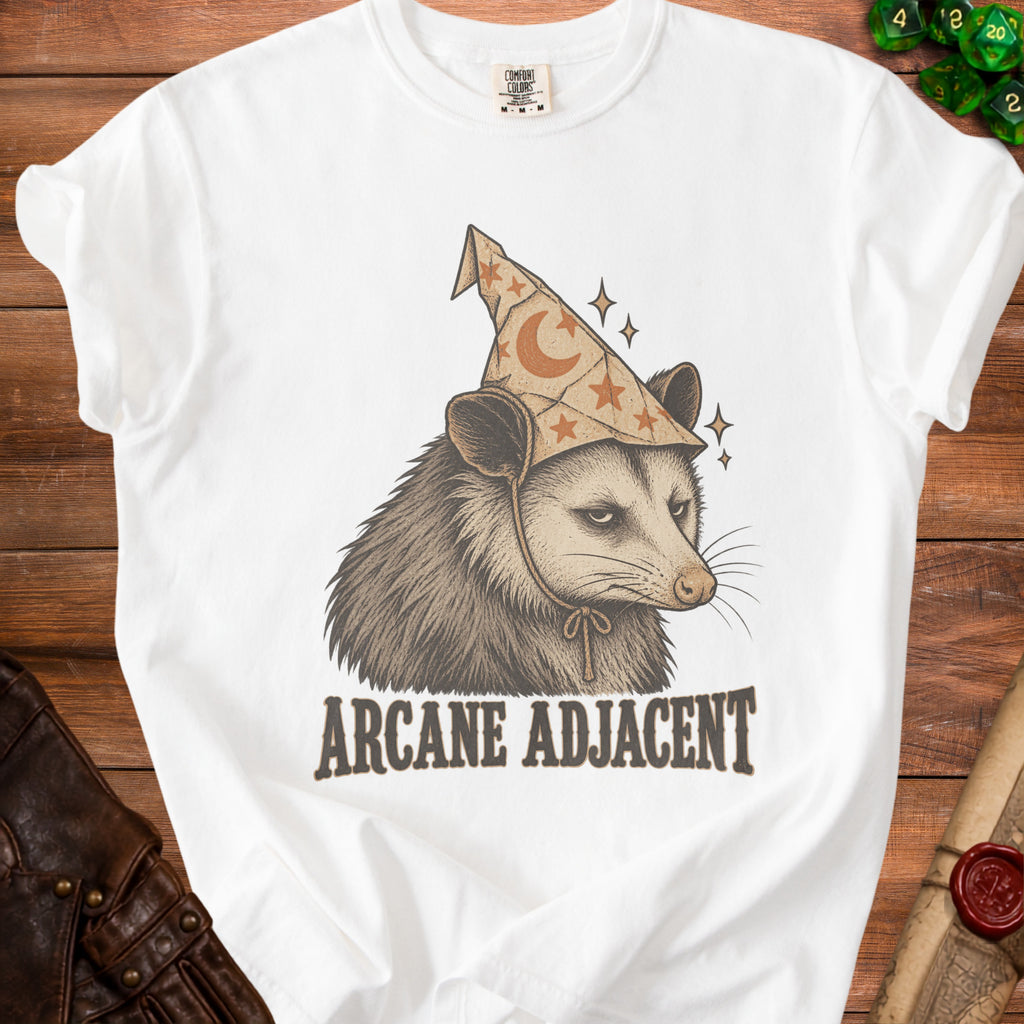 White t-shirt with a graphic of an opossum wearing a wizard hat and the text "ARCANE ADJACENT".