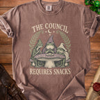 T-shirt with three frogs wearing robes, sitting at a mushroom table with text "The Council Requires Snacks."