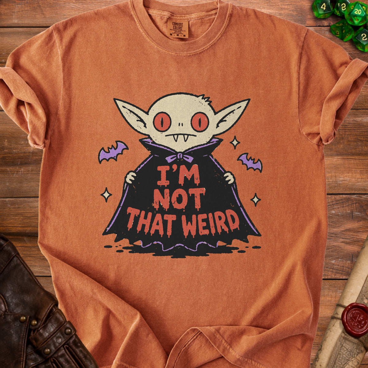 Orange t-shirt with a cartoon vampire graphic that says "I'M NOT THAT WEIRD".