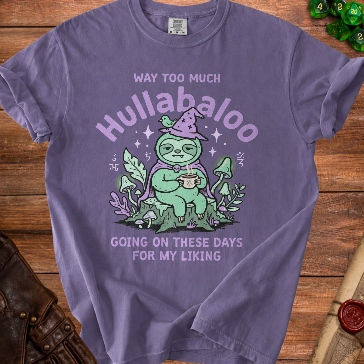 Purple t-shirt with a graphic of a sloth wearing a witch hat and holding coffee, saying "Hullabaloo".