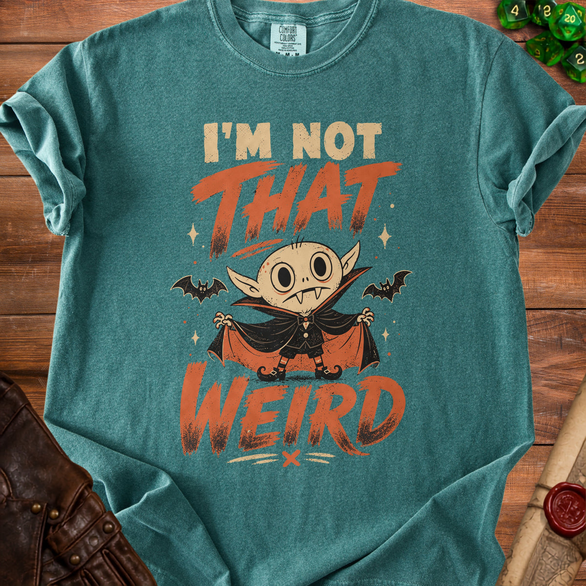 Teal t-shirt with a cartoon vampire and text "I'M NOT THAT WEIRD".