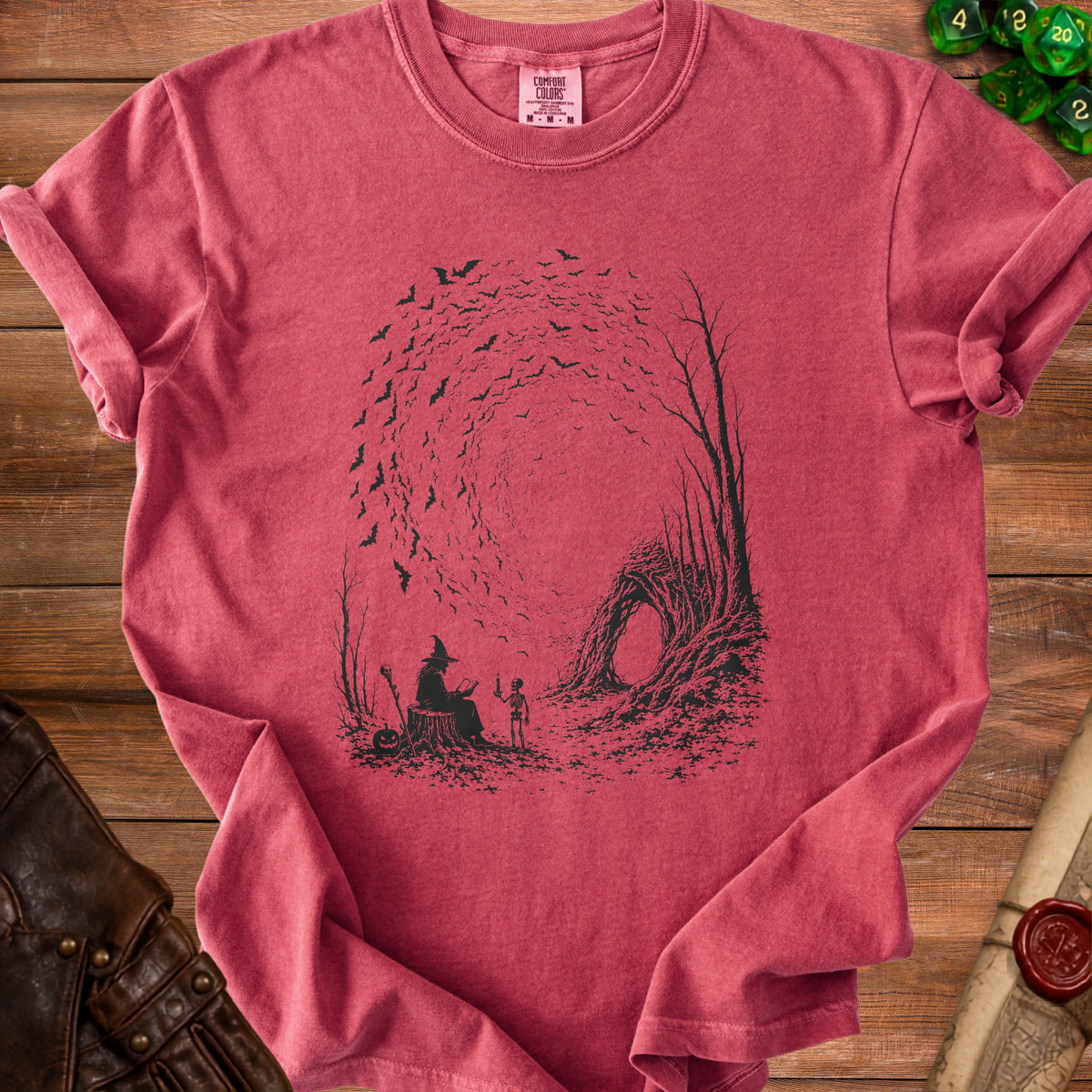 Crimson t-shirt with a graphic of a witch, skeleton, and bats in a forest scene.