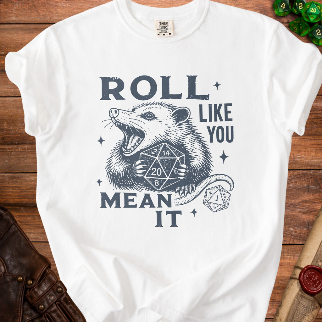 White t-shirt with a graphic of a possum holding dice and the text "ROLL LIKE YOU MEAN IT".