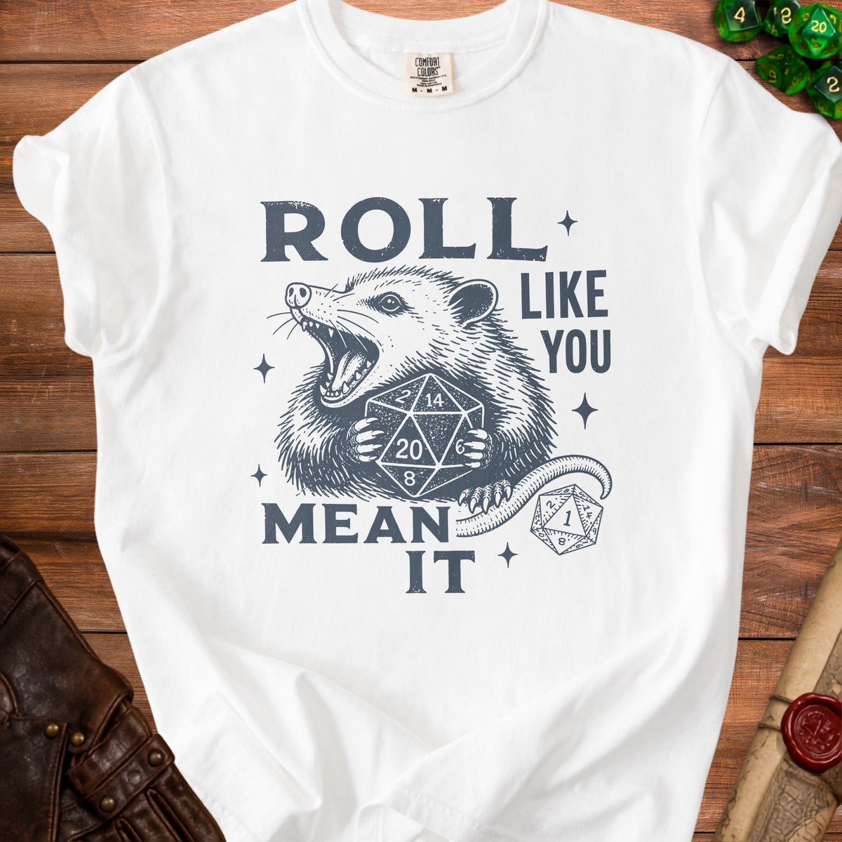 White t-shirt with a graphic of a possum holding dice and the text "ROLL LIKE YOU MEAN IT".
