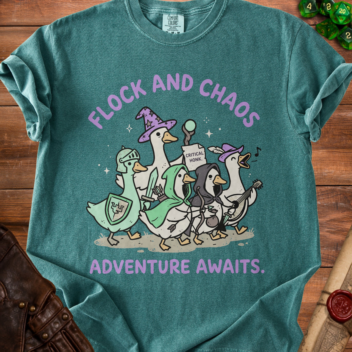 Teal t-shirt with cartoon geese dressed as fantasy adventurers. Text reads "Flock and Chaos" and "Adventure Awaits."