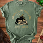 Green t-shirt with black cat wearing witch hat on books, text "No Spells. No Problems. Only Vibes."