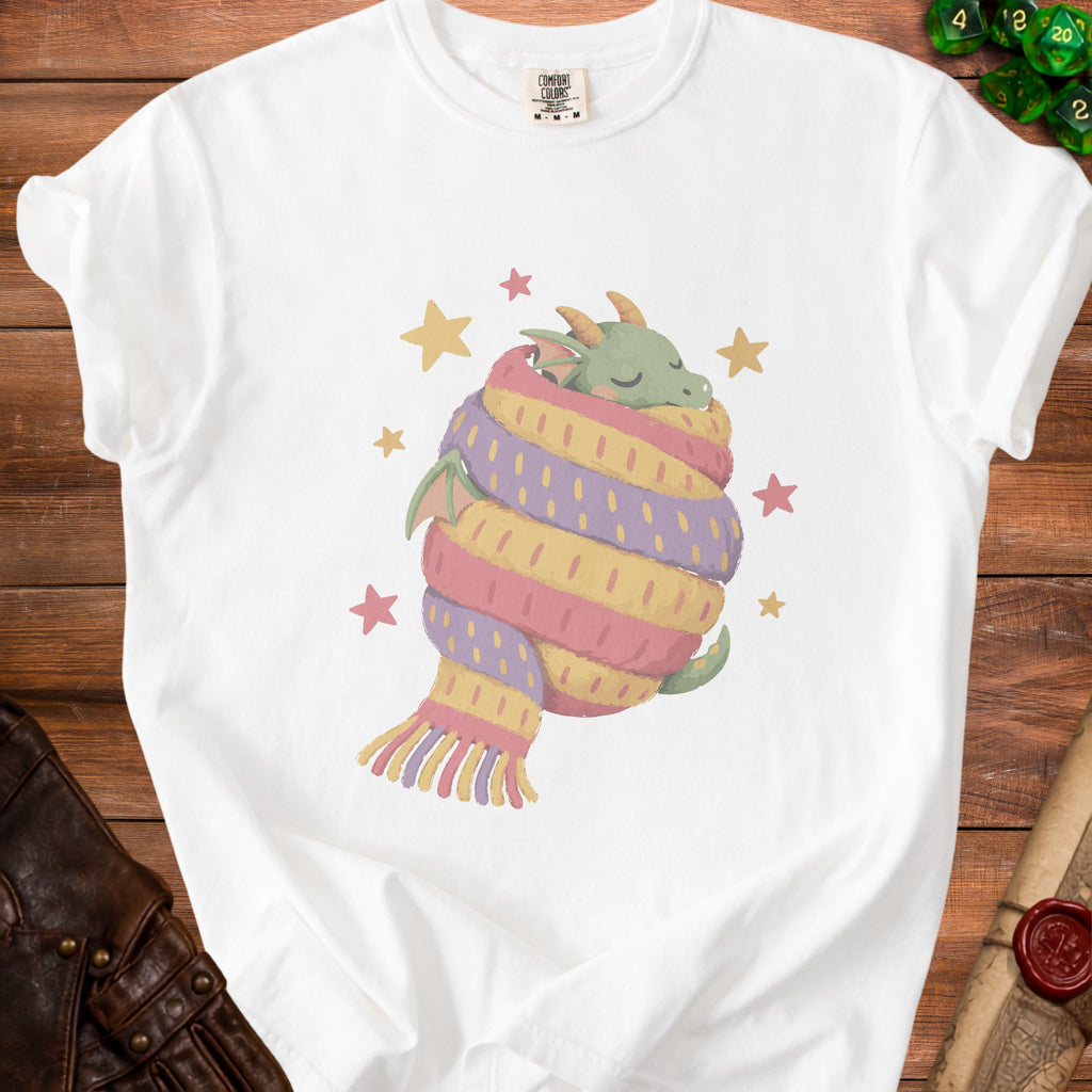 White t-shirt with graphic of a sleeping dragon wrapped in a striped scarf and stars.