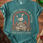 Green t-shirt with "Peace Was Never an Option" and a goose on skulls graphic.