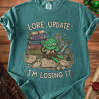 Green goblin overwhelmed by books and scrolls with text "Lore Update: I'm Losing It".