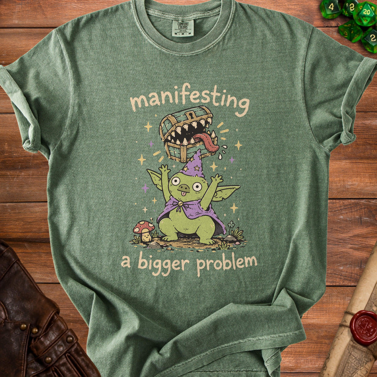 Green t-shirt with a goblin wizard and text "manifesting a bigger problem".