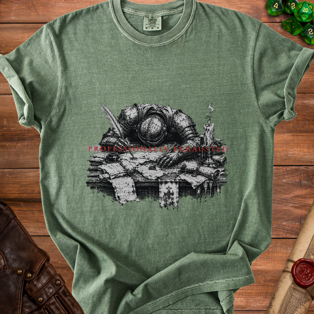T-shirt with a knight writing, surrounded by scrolls, a candle, and text "PROFESSIONALLY EXHAUSTED".