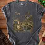 T-shirt graphic: dragon by water with a D20 die and coins.