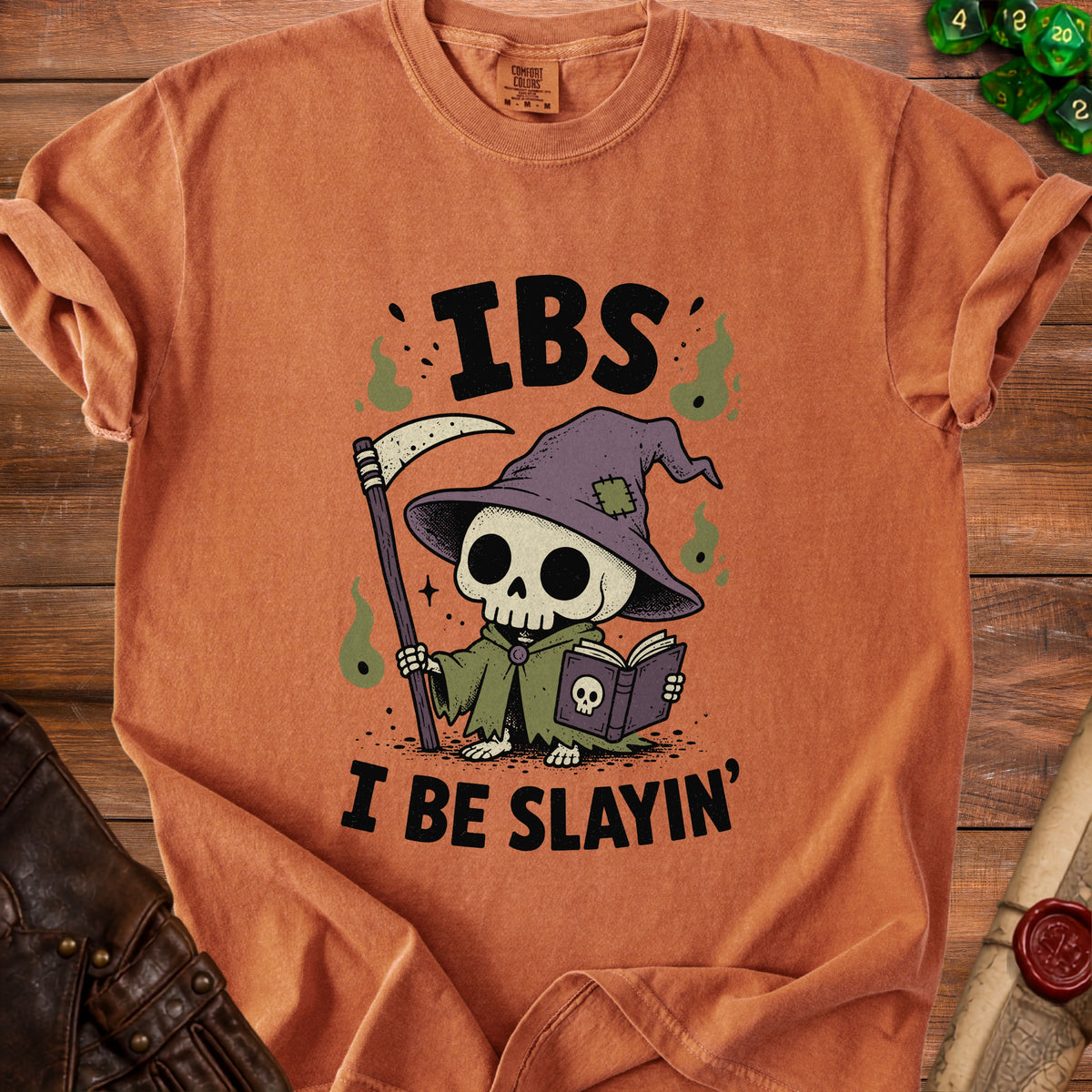 Orange t-shirt with grim reaper skeleton reading a book, text "IBS I BE SLAYIN'".