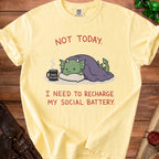 Yellow t-shirt with a cartoon dragon under a blanket and text "NOT TODAY. I NEED TO RECHARGE MY SOCIAL BATTERY."
