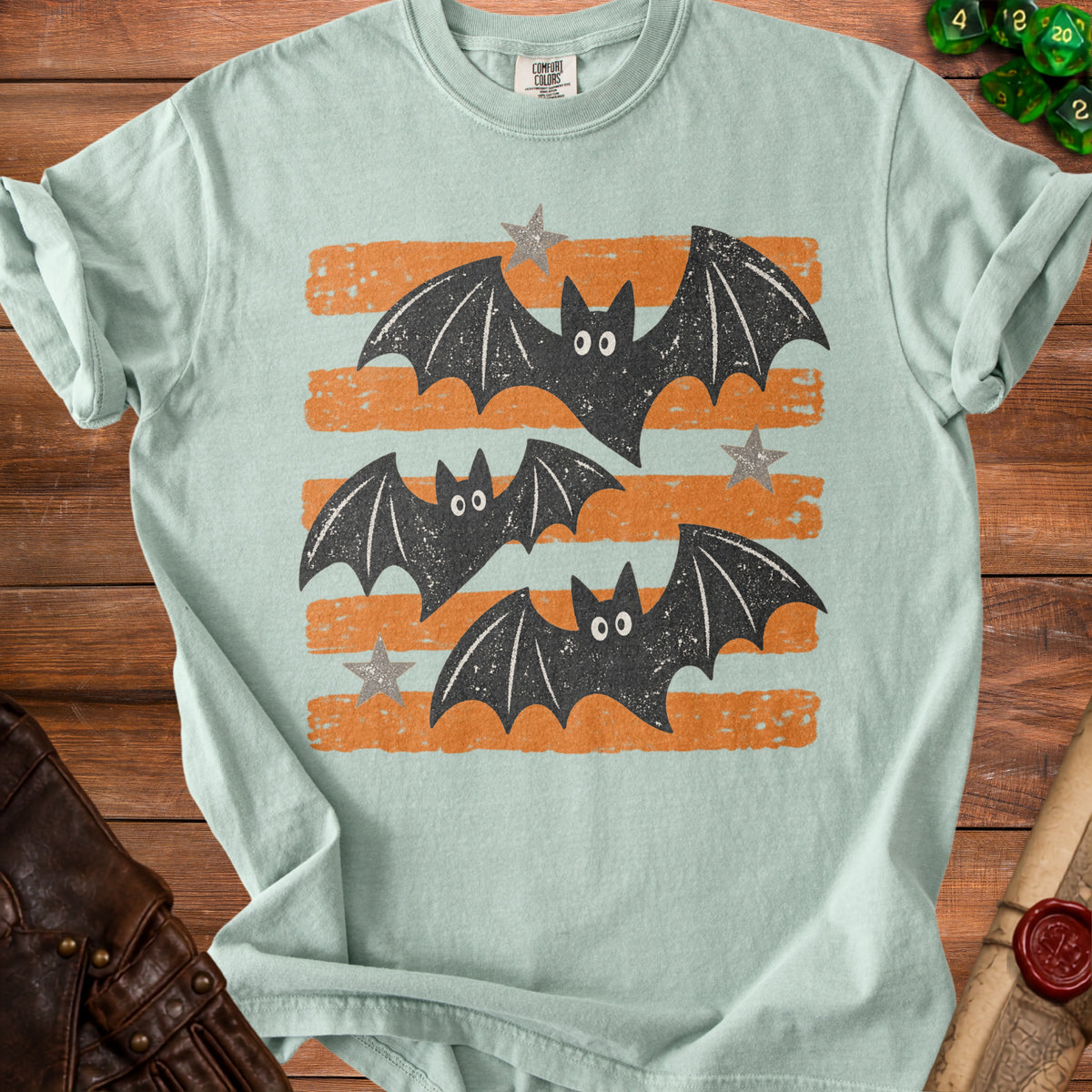 Light green t-shirt with three black bats and stars on orange stripes.