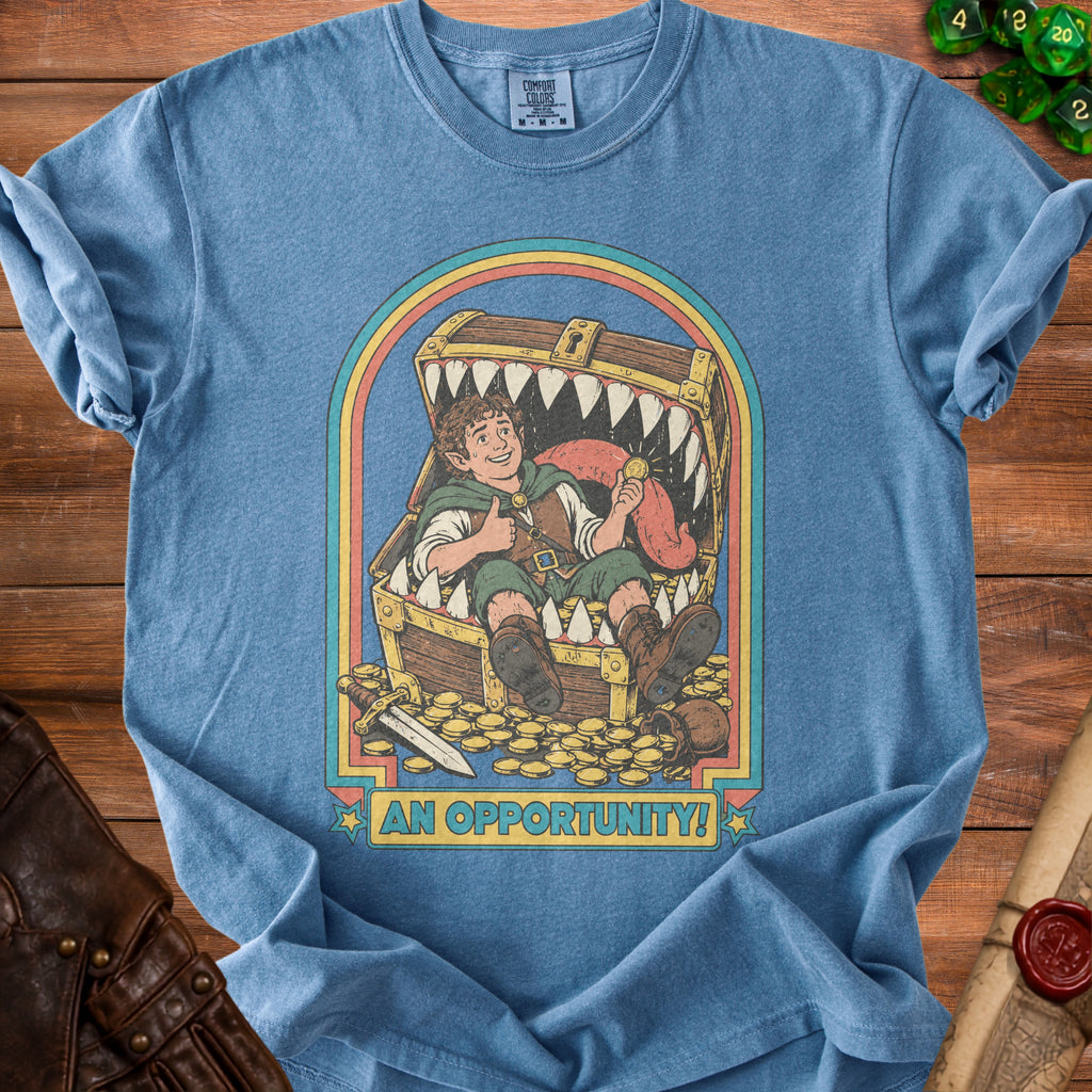 T-shirt graphic of a hobbit-like character in a treasure chest with a sword and gold coins.