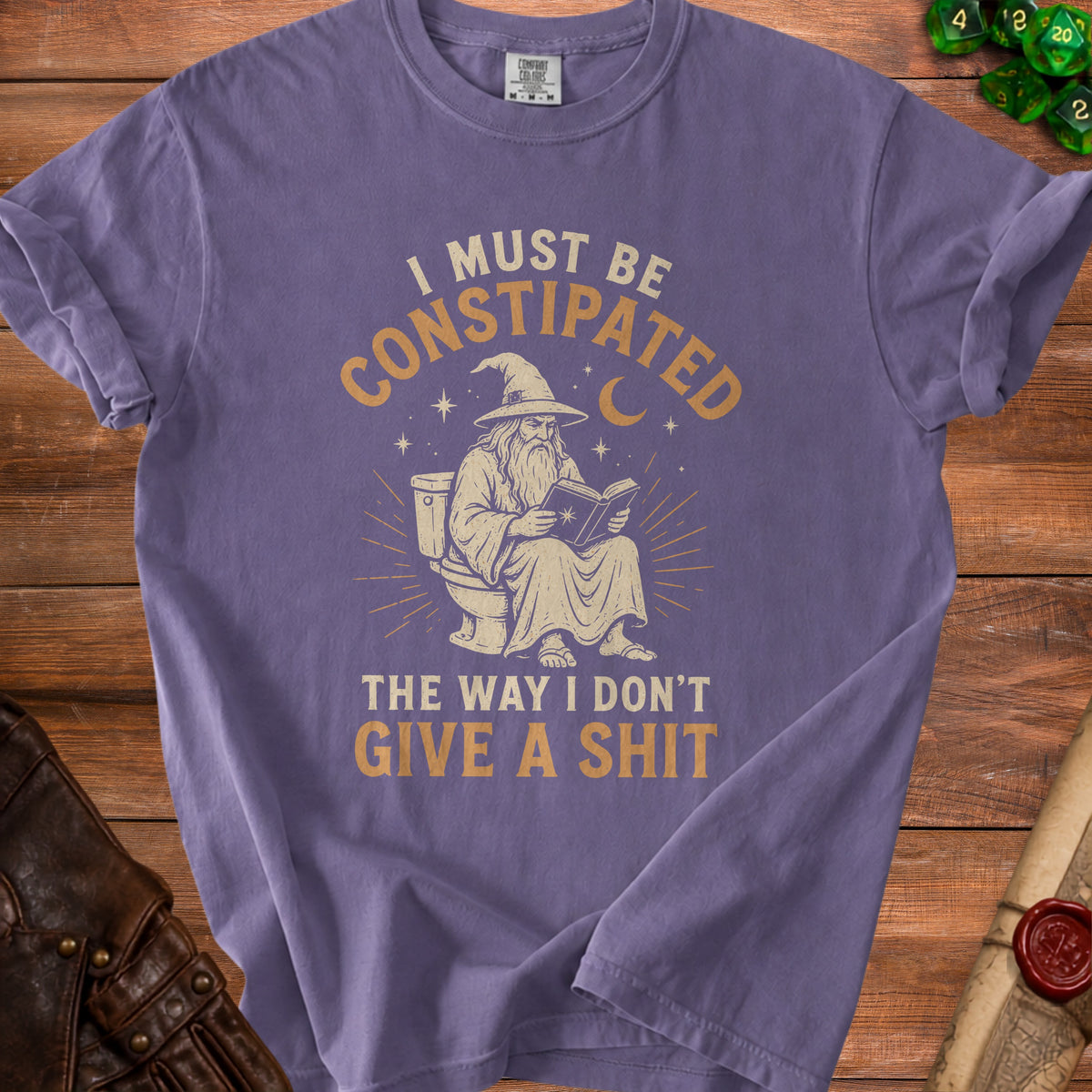 Purple t-shirt with wizard on toilet reading a book, "I must be constipated" text.