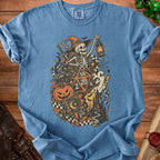 Skeleton in witch hat with lantern, black cat, dice, and Halloween imagery on t-shirt.
