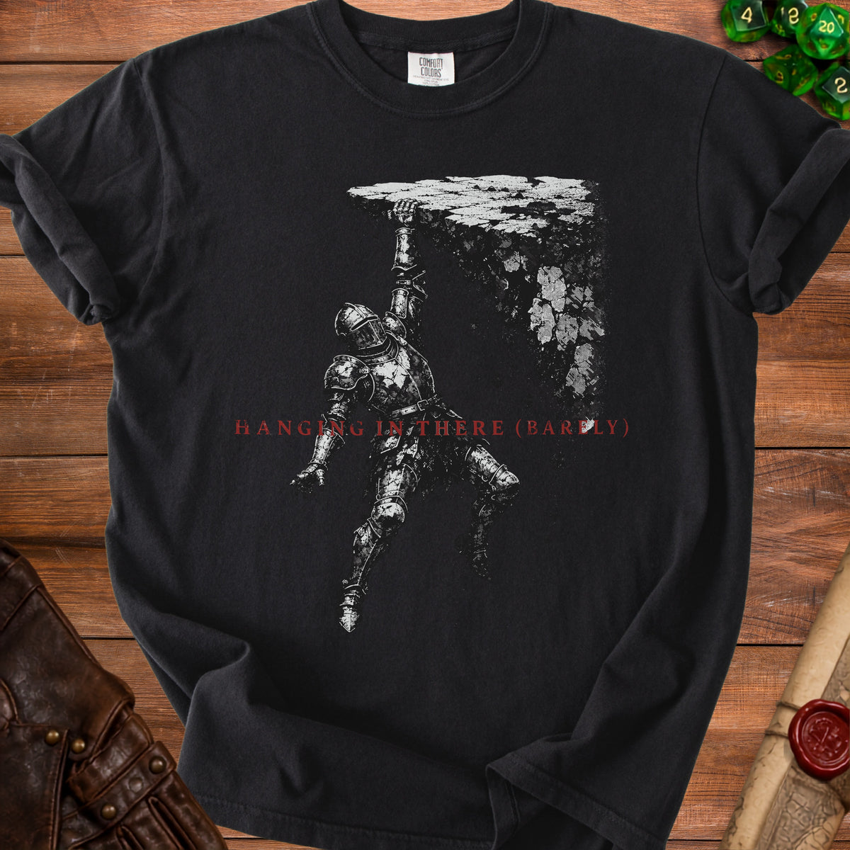 Black t-shirt with knight hanging from cliff and text "HANGING IN THERE (BARELY)".