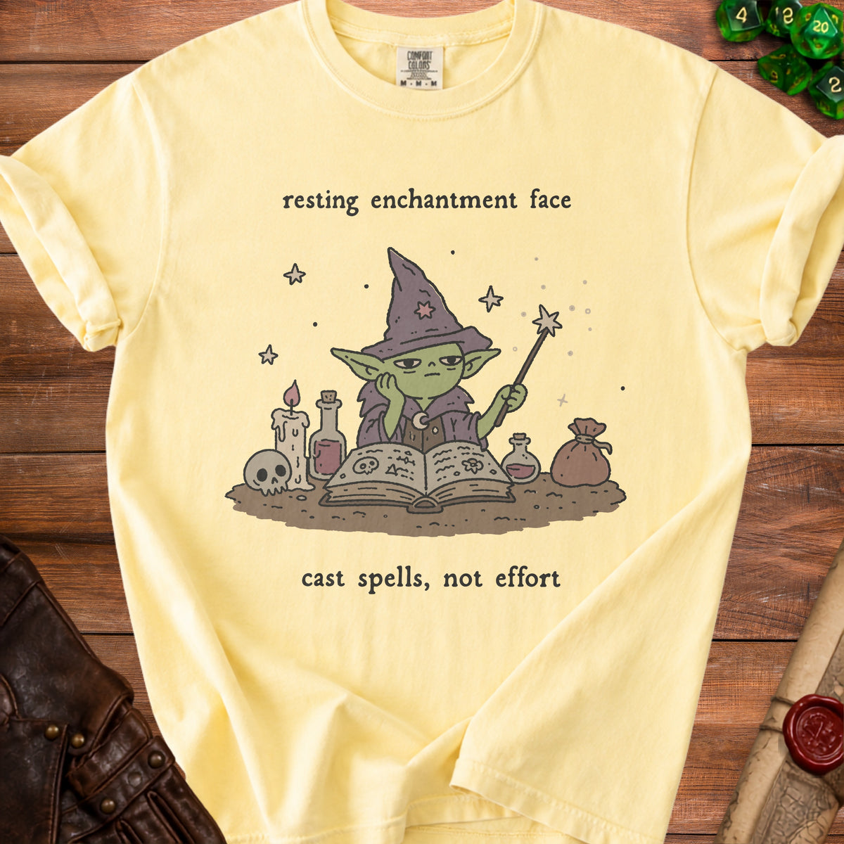 Yellow t-shirt with a wizard graphic and text "resting enchantment face cast spells, not effort."