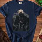 Dark blue t-shirt with a pixel art graphic of a cloaked figure on a bridge approaching a gothic castle under a full moon.