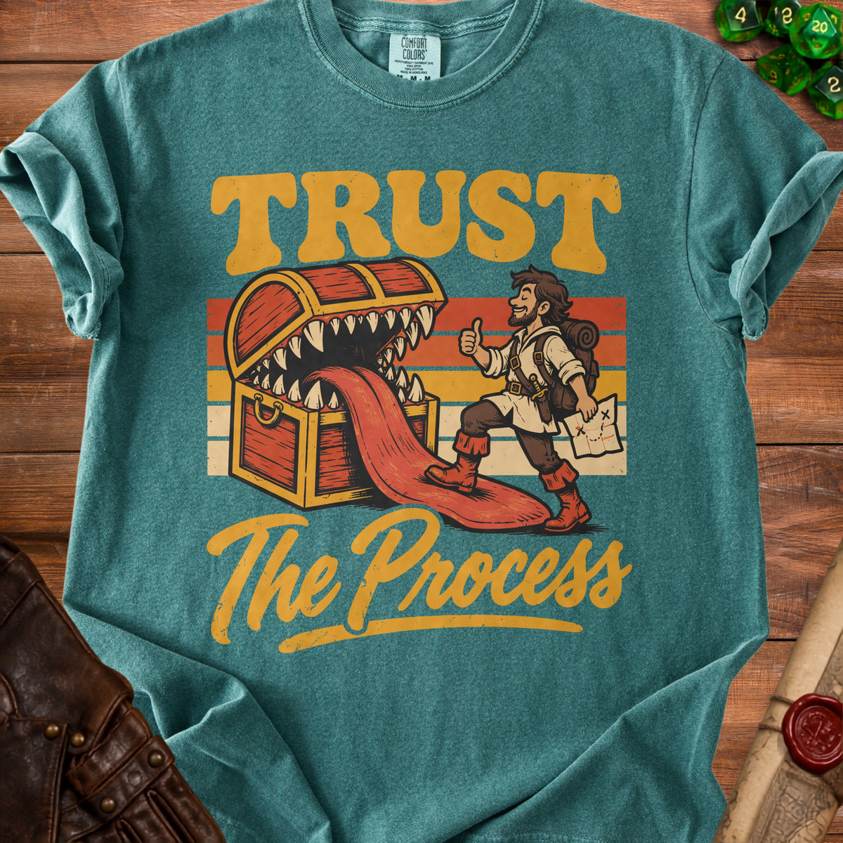 Graphic t-shirt with text "TRUST The Process", a treasure chest, and a stylized adventurer.