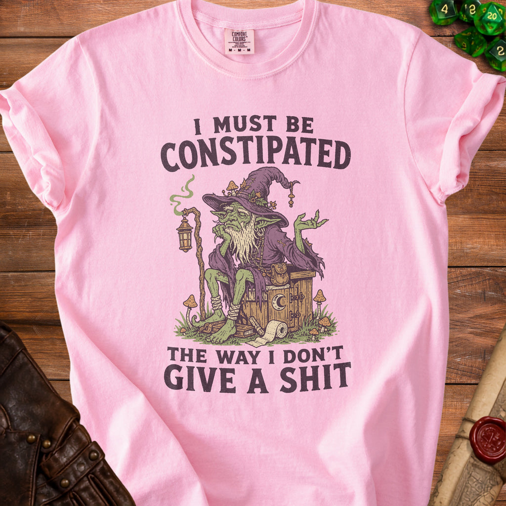Pink t-shirt with a green witch graphic and text "I must be constipated the way I don't give a shit."