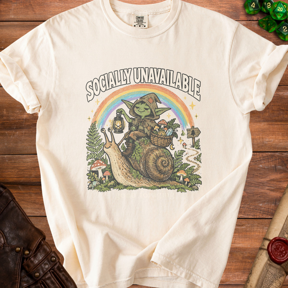 Cream t-shirt with goblin on snail, rainbow, and text "SOCIALLY UNAVAILABLE".
