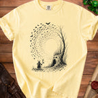 Yellow t-shirt with black graphic of a deer-headed figure and a tree with a face and bats.