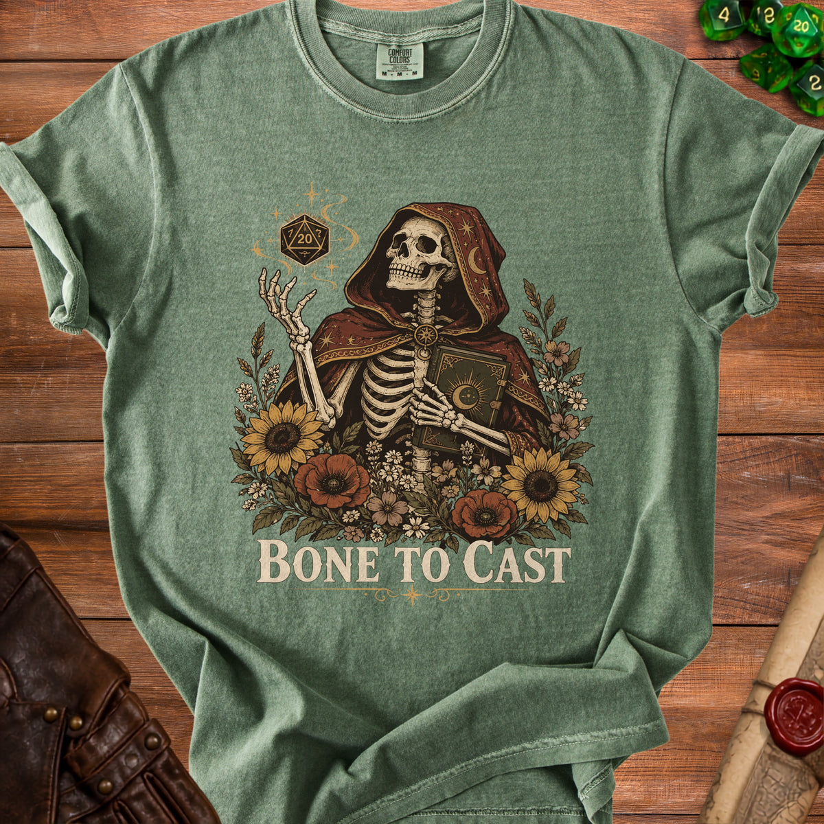 Skeleton in hooded robe holding book with sunflowers and text "BONE TO CAST".