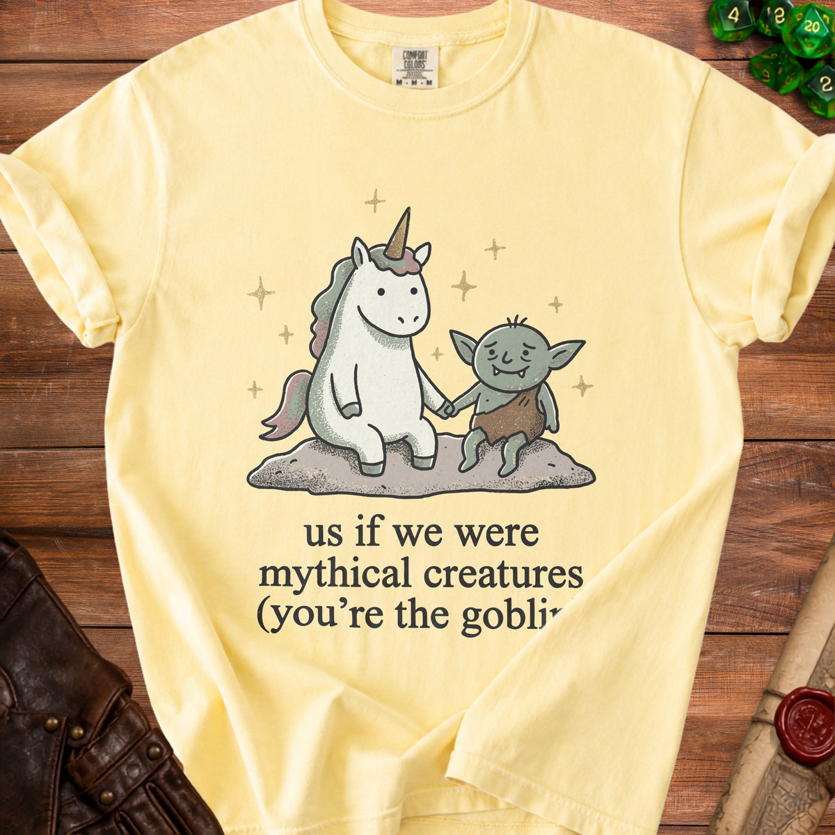 Yellow t-shirt with unicorn and goblin graphic and text "us if we were mythical creatures".