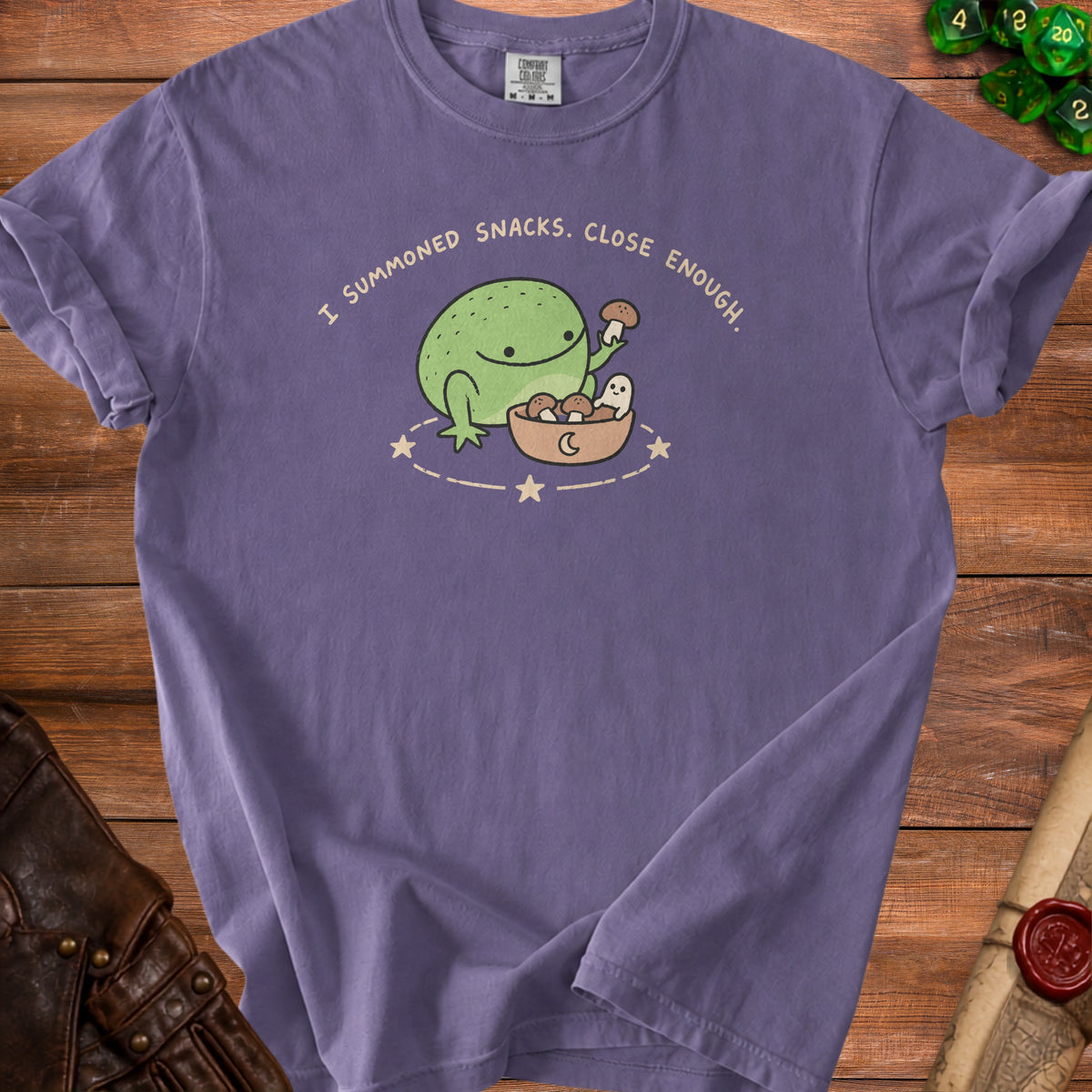 Purple t-shirt with a cartoon frog, ghost, and mushrooms with text "I summoned snacks."